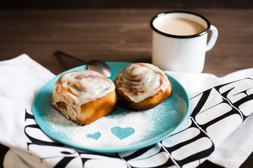 two buns with cream and a mug of coffee