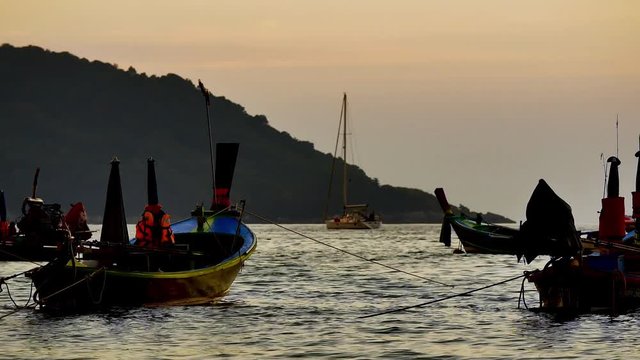 Group of  long tail boat converted to boat excursions floating in the andaman sea with golden light of the Sun before sunset and  boat background in travel or transportation concept.