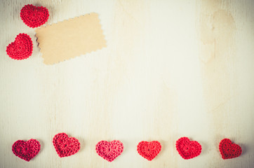 Knitted red hearts on a vintage wooden background