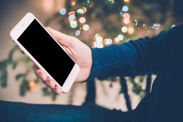 man relaxing at home with smartphone in his hand, cozy holiday e