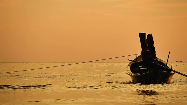 Travel video silhouette long tail boat and The fisherman are maintenance ship. After the boats go out, such as catching the fish. Trips are made every day with  golden light of the Sun  before sunset.