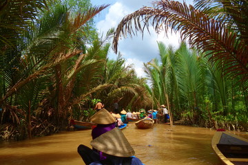 My Tho, Vietnam: Tourist at Mekong River Delta jungle cruise with unidentified craftman and fisherman rowing boats on flooding muddy lotus field in Mekong delta into Ho Chi minh city - obrazy, fototapety, plakaty