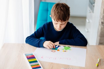 8 letni chłopiec maluje kredkami obrazek lurkę dla swojej babci na Dzień Babci - obrazy, fototapety, plakaty