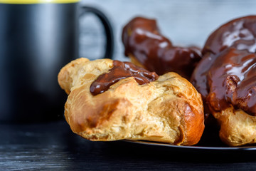 Coffee and chocolate eclairs on a dark wooden background
