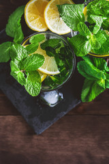 Top view of cool fresh lemonade in glasses with lemon and mint on a wooden table.