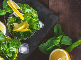 Top view of cool fresh lemonade in glasses with lemon and mint on a wooden table.