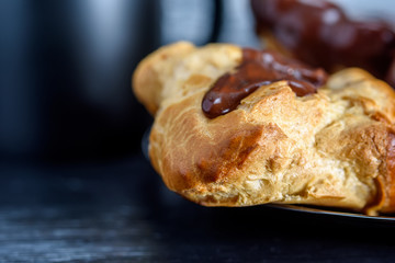 Coffee and chocolate eclairs on a dark wooden background