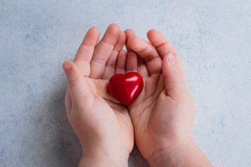 Child hands holding red heart. Card for Valentines day. World heart day, world health day, healthcare, donate and family insurance concept. Blue Background