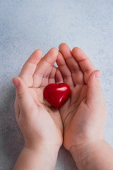 Child hands holding red heart. Card for Valentines day. World heart day, world health day, healthcare, donate and family insurance concept. Blue Background