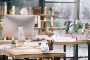 blueprints, documents and computer at workplace in modern architect office