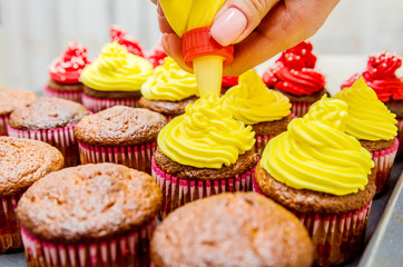 The process of decorating the cakes with yellow cream.