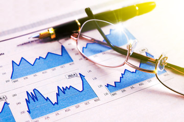 Datos de mercado y comercio de bolsa.Fondo de economia y finanzas.Pluma,gráficos y gafas