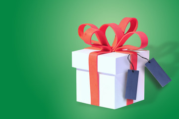 White gift box and red ribbon with blank card on green background, celebration concept