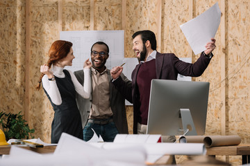 celebrative team of architects with papers at modern office