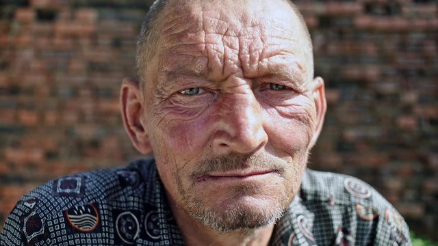 Portrait of a poor old elderly man who looks scornfully at the camera