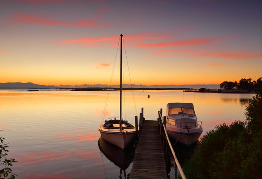 Boats moored to jetty at sunrise