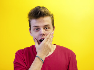 Portrait of a young man with a shocked facial expression isolated on a yellow background