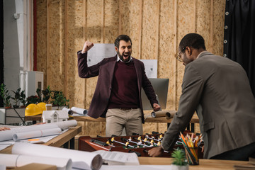 young architects playing table football in office