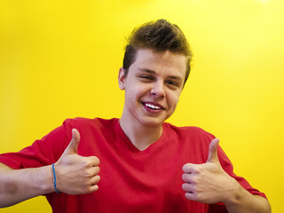 super satisfied young casual man making ok thumbs up sign hands on yellow background