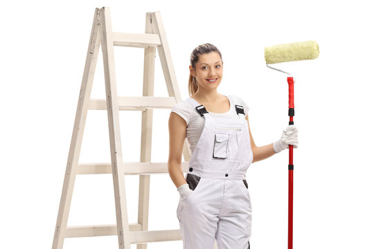 Female painter holding a paint roller in front of a ladder