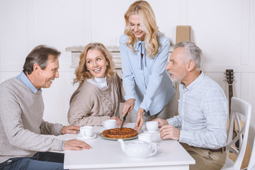 woman cutting pie on table while friends sitting