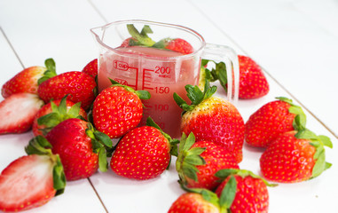 Closeup the strawberry juice and red strawberry around plastic jar,on timber board,blurry light around.