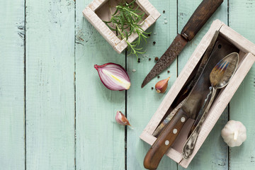 Culinary background. Vintage kitchen utensils, garlic and rosemary on a wooden kitchen table. Flat lay, top view with copy space.