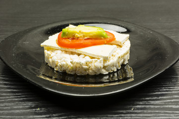 Rice cake sandwich with cheese, tomato and avocado.