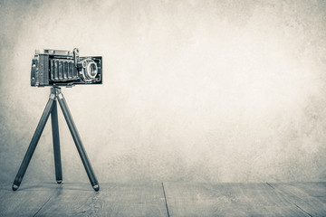 Retro old outdated manual film camera from USSR circa 1950s on wooden table. Vintage style sepia...