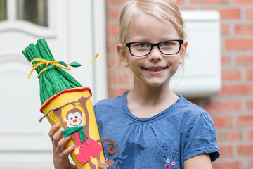 Ein 5 Jahre altes Mädchen vor der Haustür mit Schultüte auf dem Weg zur Einschulung