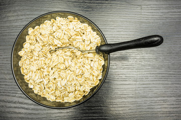 A spoon in a bowl with dry oat flakes.