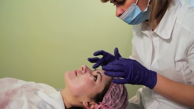 Beautician gets a soothing cream on the woman's face. Reddened, irritated skin after mesotherapy. Close-up