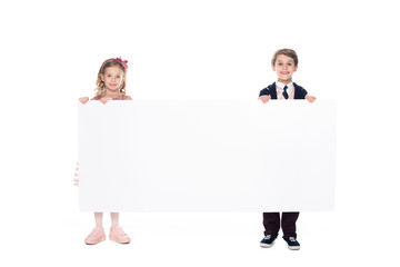 cute little kids holding blank banner and smiling at camera isolated on white