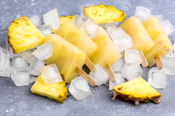 Delicious Homemade Pineapple Popsicles on Ice Cubes Gray Background Summer Food Concept Above Horizontal