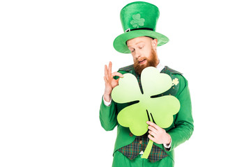 handsome leprechaun in green suit holding clover, isolated on white