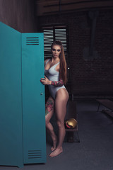 Young woman standing in locker room. Pretty fitness girl ready for a workout in gym