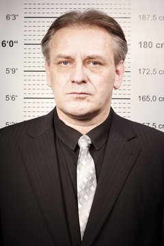 Criminal man portraited in front of mug board