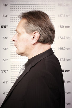 Criminal man portraited in front of mug board