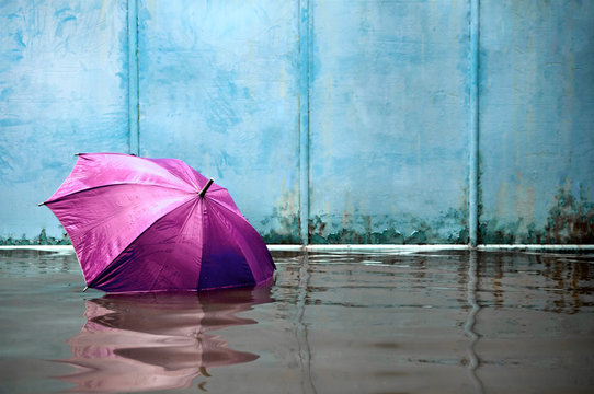 Concept of magenta umbrella floating on flooded street and waiting for help me after the rain.