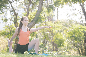 Beautiful woman doing yoga exercises in the park. Concept of healthy lifestyle.