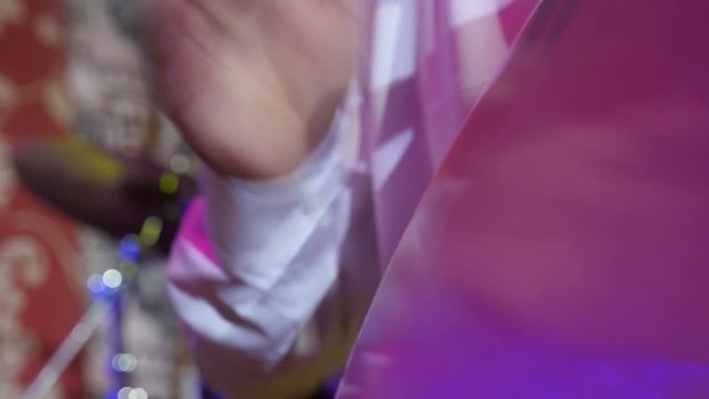 closeup Hands play the drums, where all around the drum the bright stage lights in the smoke live concert slow motion