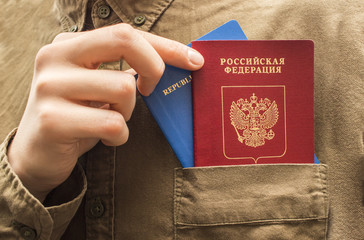 A man takes out two different passports from his shirt pocket close up. Tourism and travel concept....