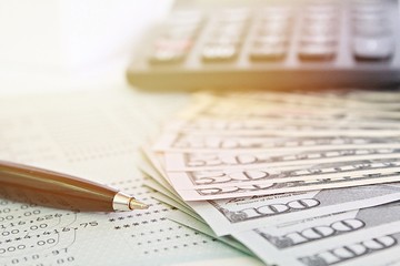 Business, finance, investment, savings or accounting concept : American Dollars cash money, calculator and savings account passbook or financial statement on table