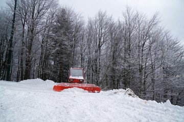 Snow plow on the hill with trees. Slovakia