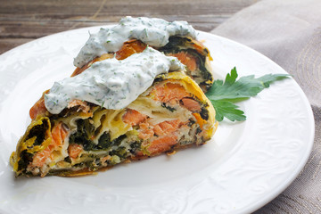 Strudel pie with salmon and spinach, served on wood table