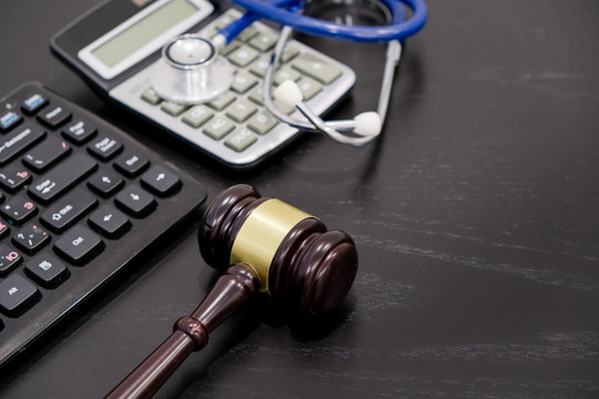 Wooden judge gavel, calculator and stethoscope on table. black background, the concept of medical malpractice, a workplace lawyer. fraudulent activity patients