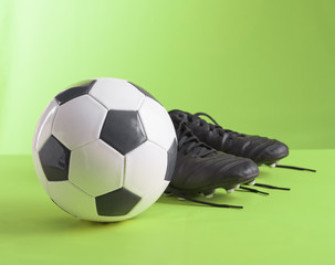 Football shoes and Soccer Ball against on green background,Copy space.