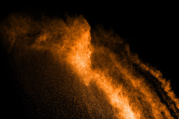 Naklejka na ściany i meble abstract orange powder explosion on black background. abstract orange dust splattered on black background. Freeze motion of orange powder splash.