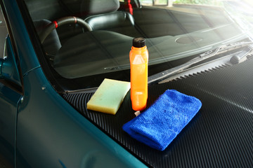 the sponge,the blue towel  and orange wax  cream  bottle on the engine skirt