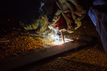 Welder perform welding to the metal plate at roof floor of manufacturing factory by using steel welding electrode in offshore oil and gas industrial operation, Blue collar jobs